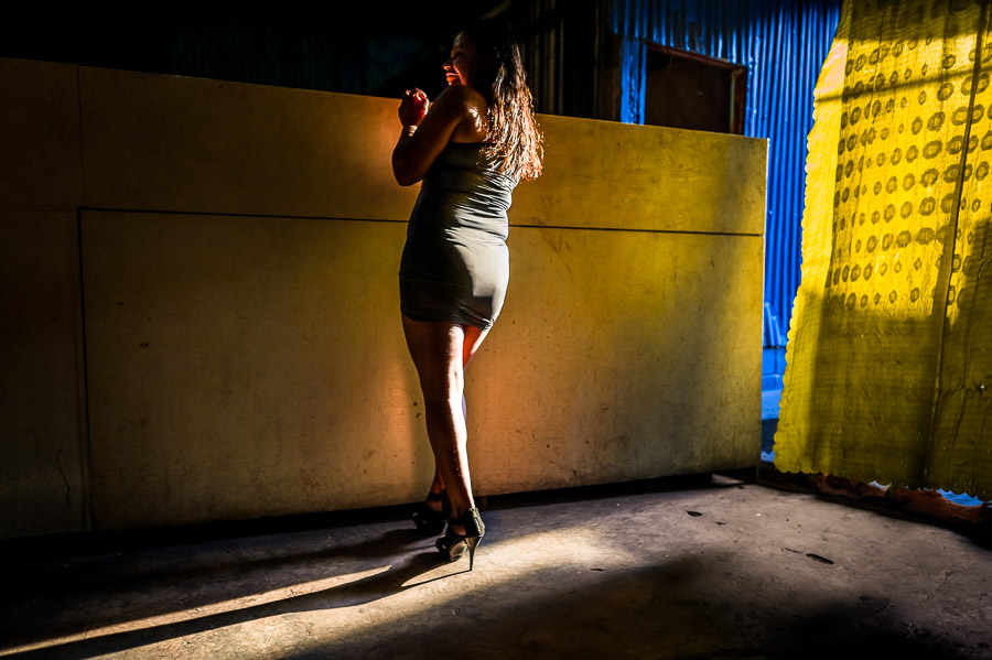 A Salvadoran sex worker stands at the bar while waiting for clients in a street sex club in San Salvador, El Salvador.