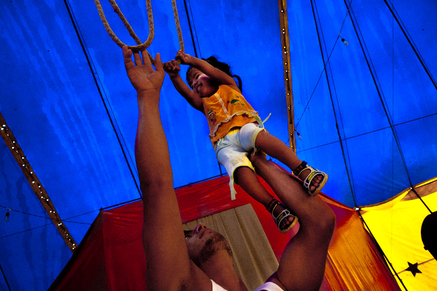 A little Colombian girl does a trapeze training with help of his father.