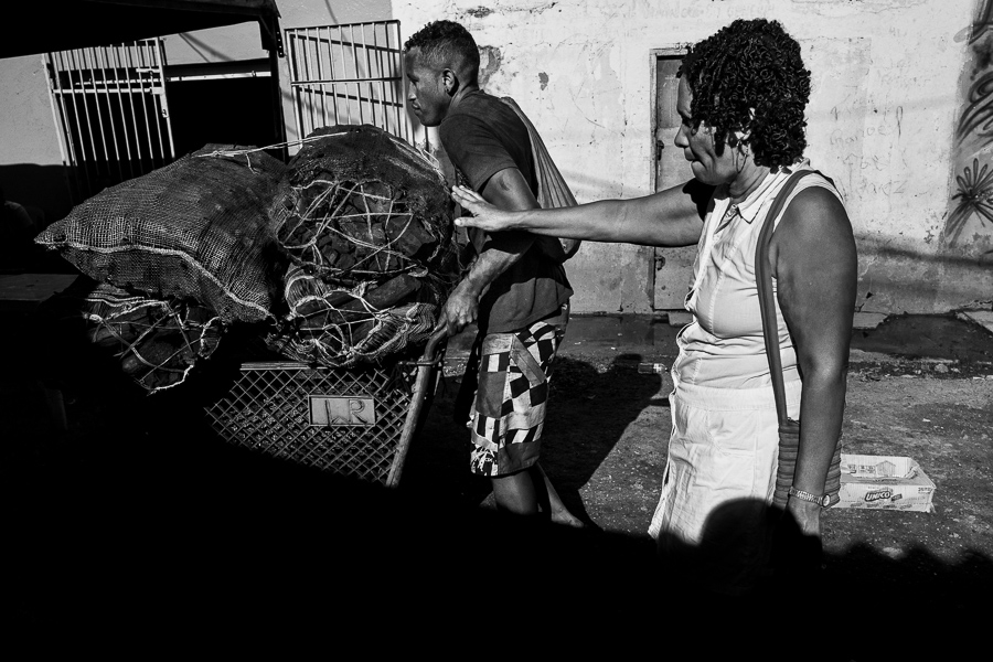 An Afro-Venezuelan carrier pushes a shopping cart loaded with bags of charcoal for sale at a street market in Cartagena, Colombia.