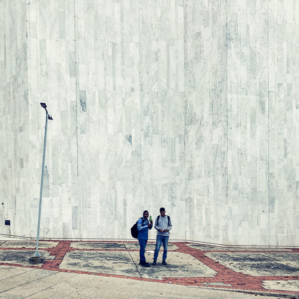 Young Afro-Colombian men talk on the street in front of Banco de la República in Barranquilla, Colombia.