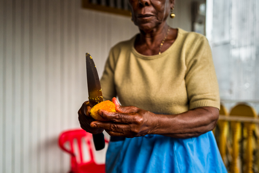 An Afro-Colombian woman peels a freshly cooked chontaduro (peach palm) fruit with a knife on the porch of her house in Quibdó, Chocó, Colombia.