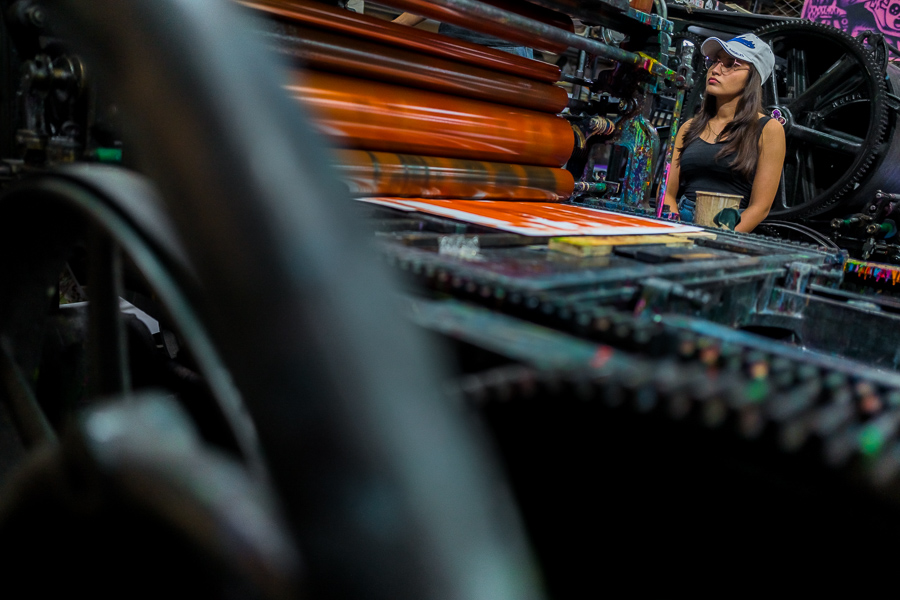 A young Colombian student of graphic design observes the printing process on the historical letterpress machine at a printing workshop in Cali, Colombia.
