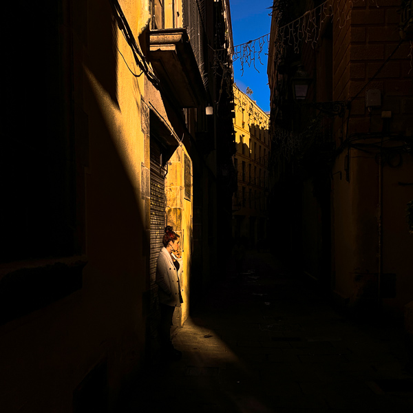 A Catalan woman smokes a cigarette in a narrow street of Barri Gòtic (the Gothic Quarter) in Barcelona, Spain.